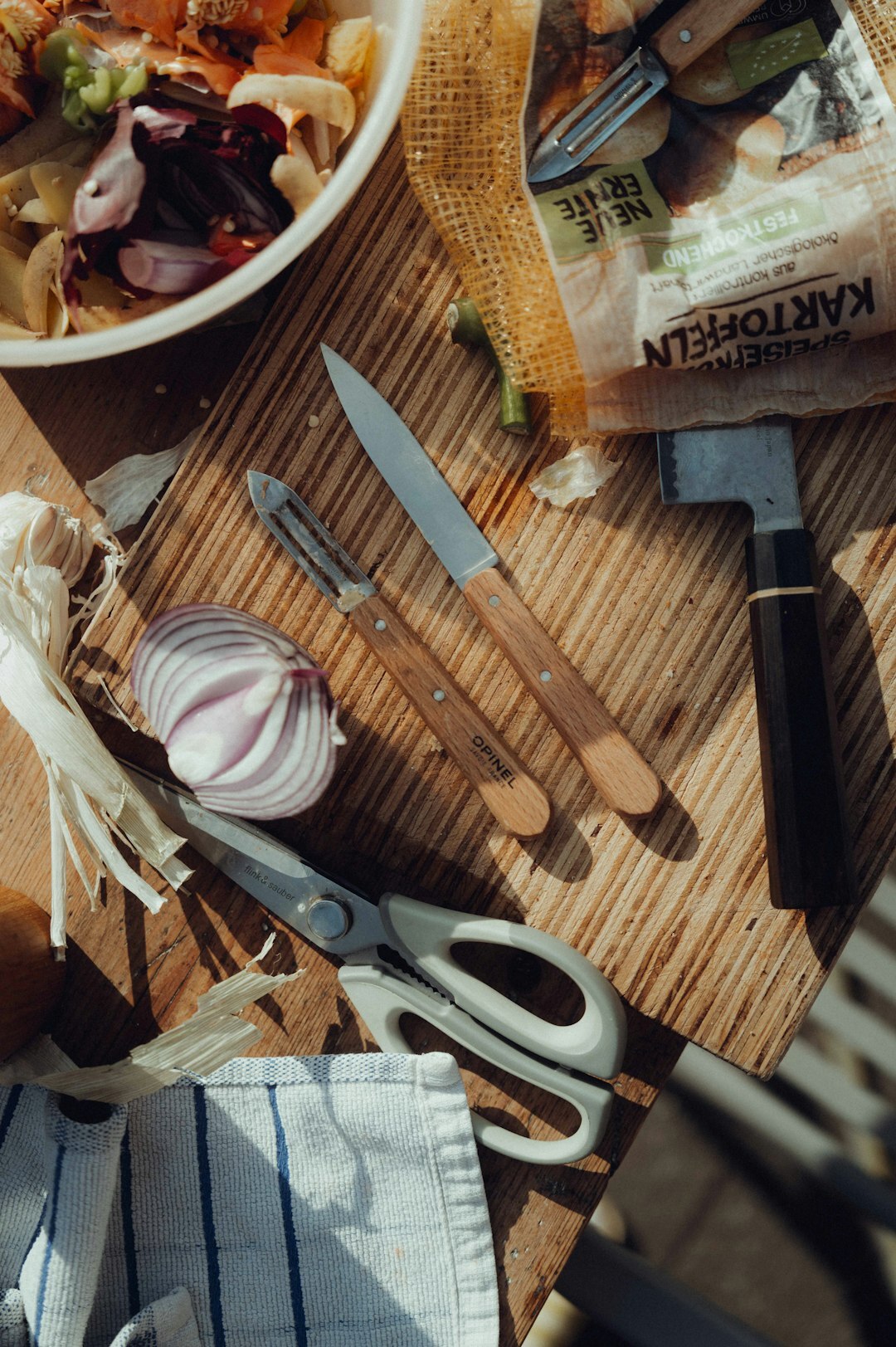 Overhead view of a wooden kitchen table with fresh vegetables and cooking utensils